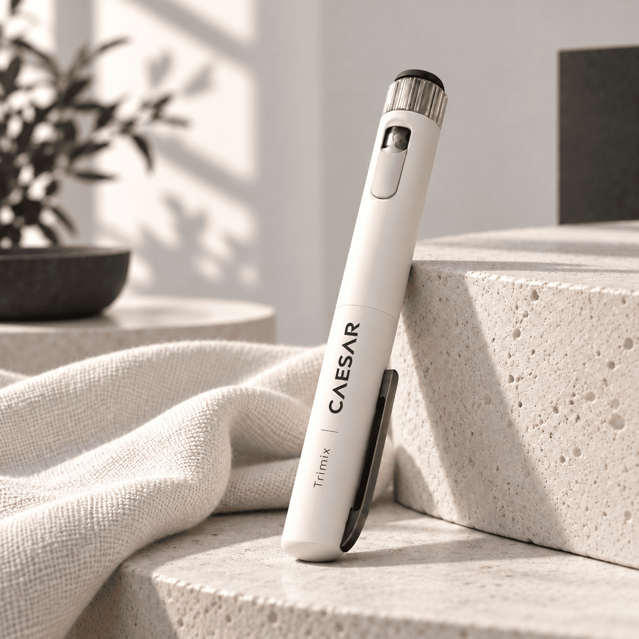 Ivory pen labeled Caesar Trimix leaning against pale stone beside linen